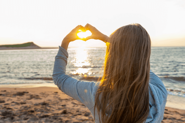 Hopeful girl holding hands in heart shape